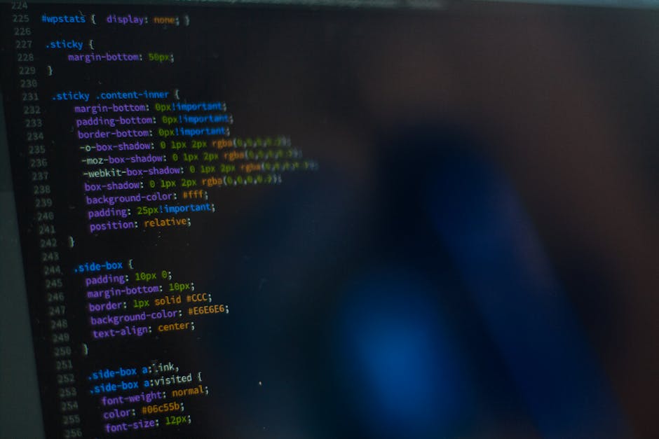 A close-up view of a computer screen displaying HTML code, including elements such as <html>, <head>, <title>, and <link>. The code features syntax highlighting with keywords in blue, attributes in or